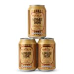 Three gold cans of Royalty Non-Alcoholic Ginger Drink stacked in a pyramid against a clean white background, showcasing the traditional English and Arabic labeling
